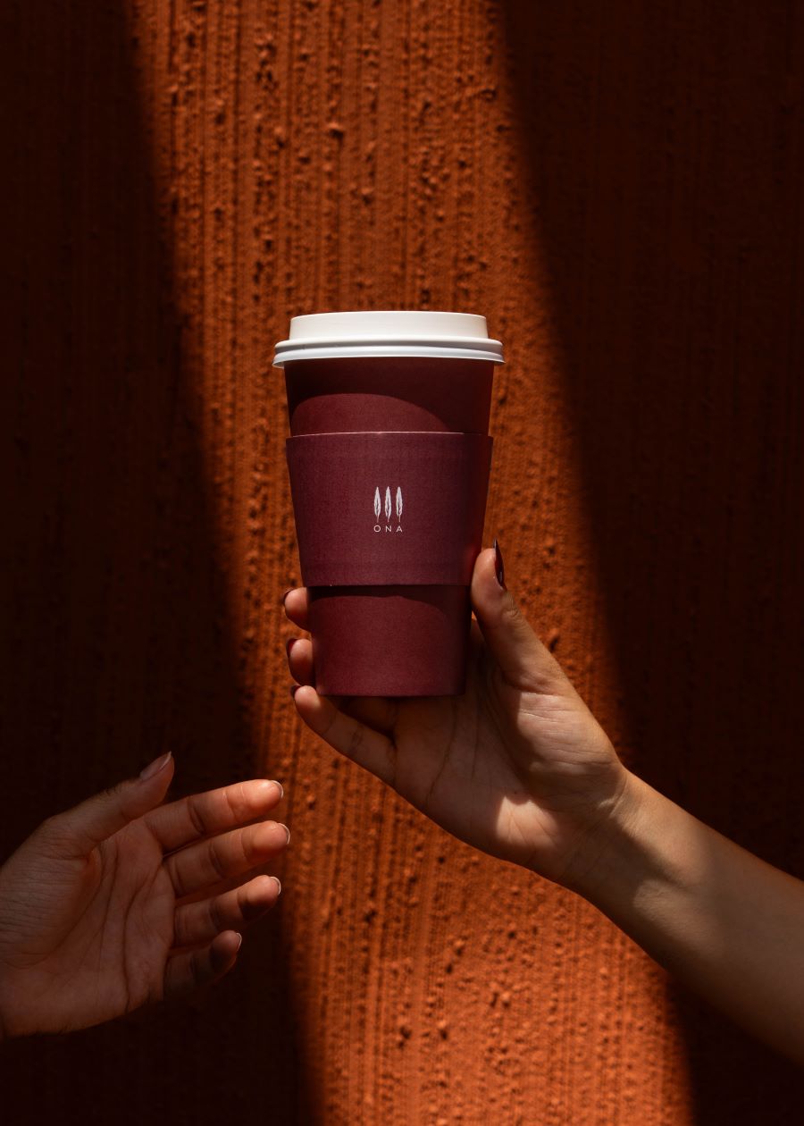 ONA branded coffee cup being handed over