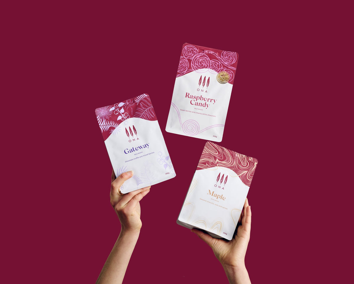 Three ONA coffee bags held up against a magenta background